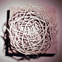 porcelain coiled structure mounted on wood panel